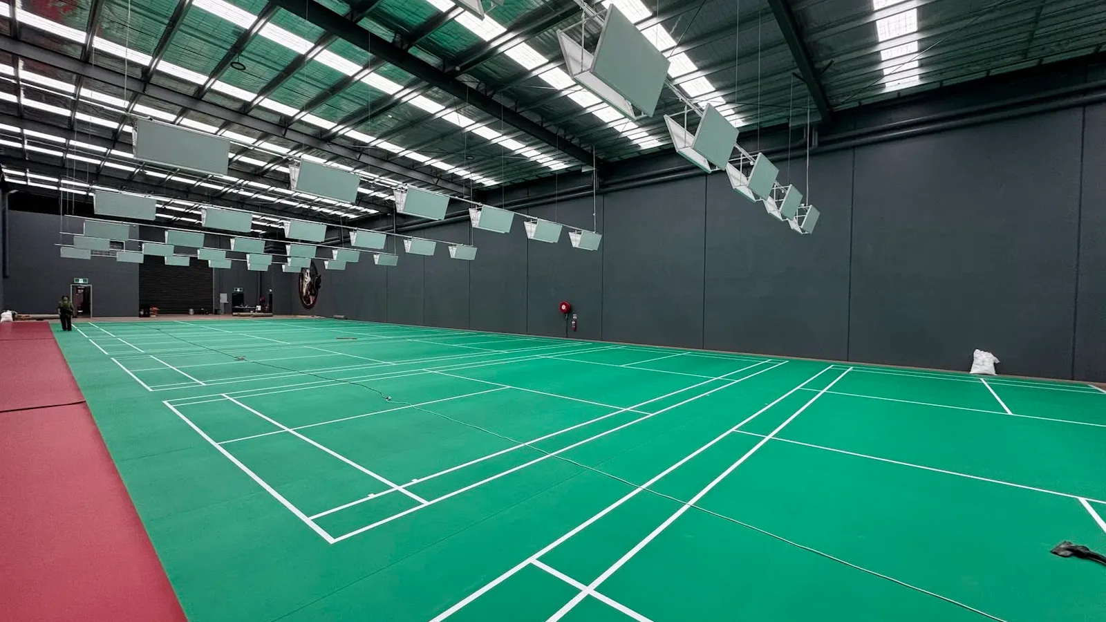 The playing hall at Stormers R Badminton Centre in Ravenhall, Melbourne — rows of green badminton courts under a high warehouse roof